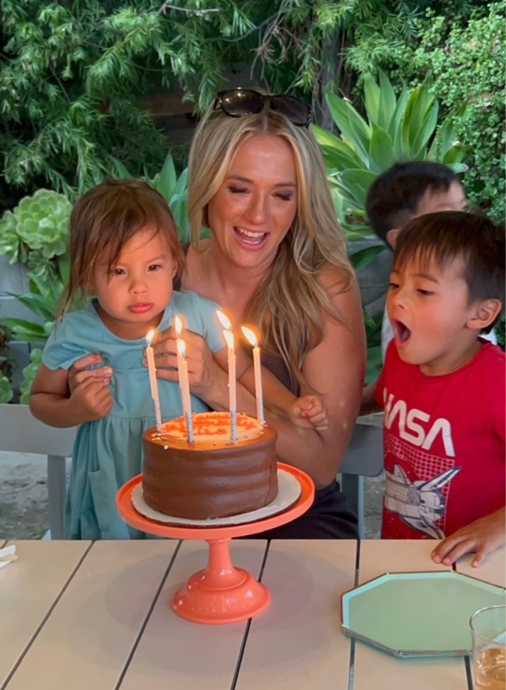 Mother and children blowing out candles on a birthday cake