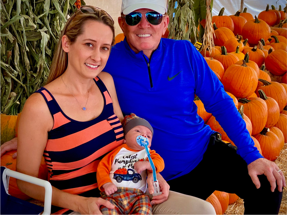 Parents holding infant in a pumpkin field