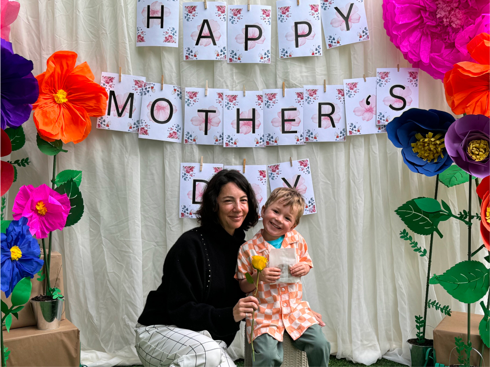 Mother and son posing in front of Happy Mother's day sign